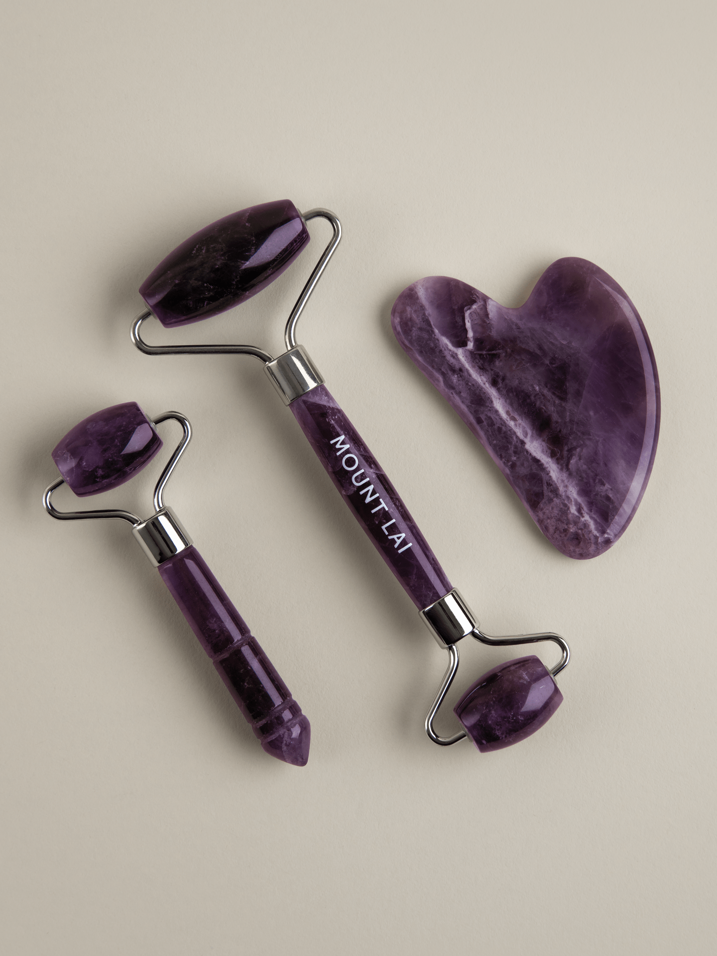 Amethyst Trio Calming Facial Set containing award winning gua sha lifting tool, de-puffing facial roller & mini facial roller